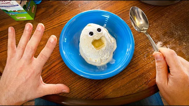 Hands on a table beside a blue plate holding a scoop of ice cream with a surprised face