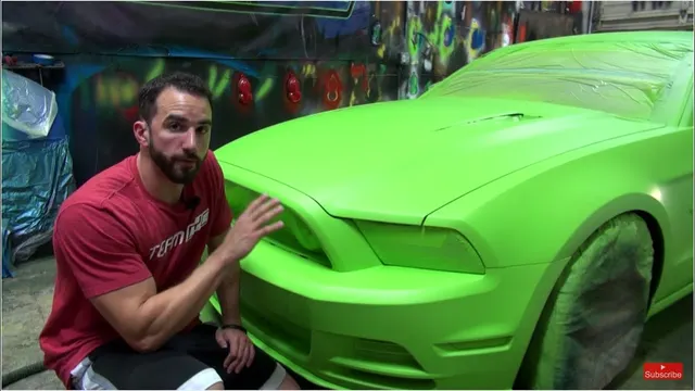 Fonzie kneeling beside a Mustang dipped in matte lime green