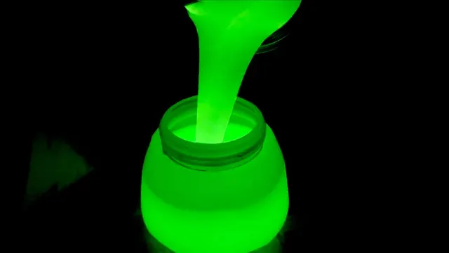 Glow-in-the-dark green pigment pouring into a jar against black