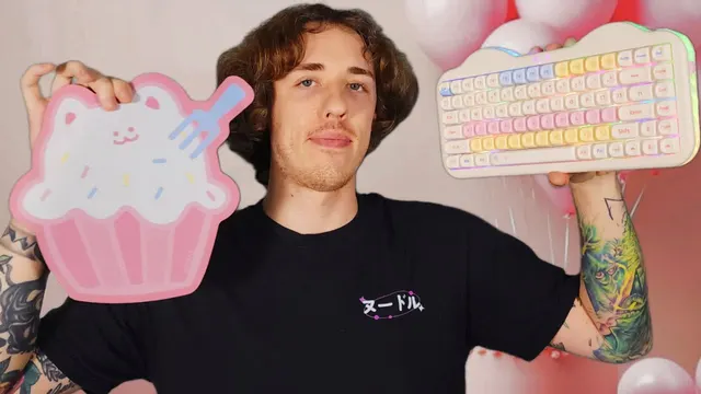 NoodleNick holding a pastel cat-themed keyboard and a cake-shaped box