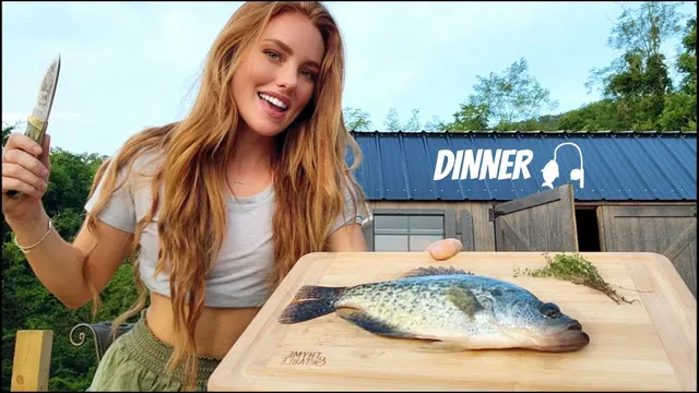 Heidi holding a knife beside a crappie on a cutting board